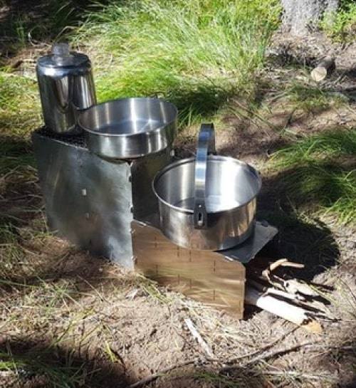 Two pots and a percolator heating together on a StealthFyre stove in tall grass